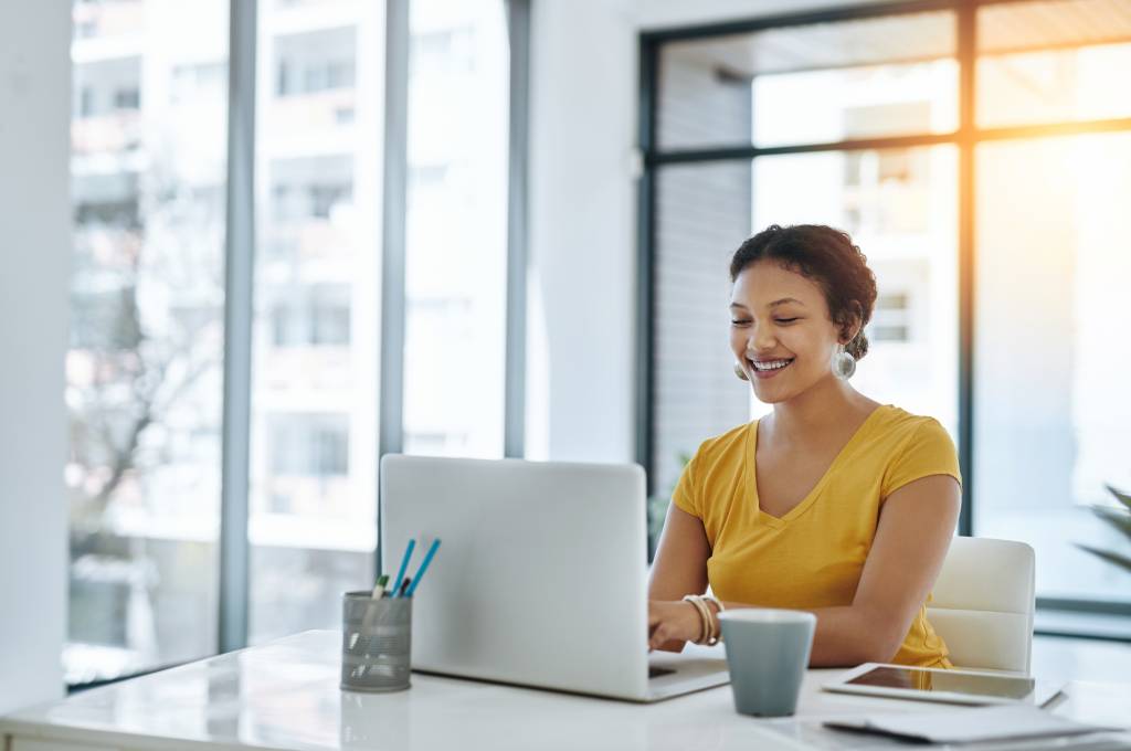 A smiling professional woman sitting at a desk doing work in a temporary office space